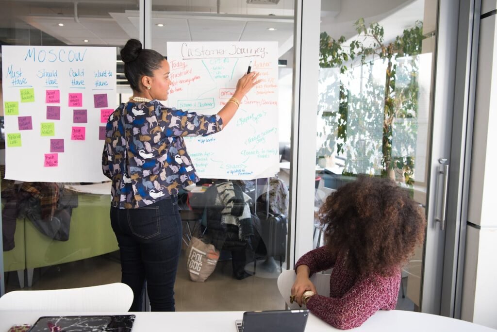 Two Women Having a Meeting Inside Glass-panel Office